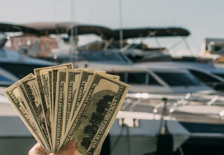 a person holding money in front of boats