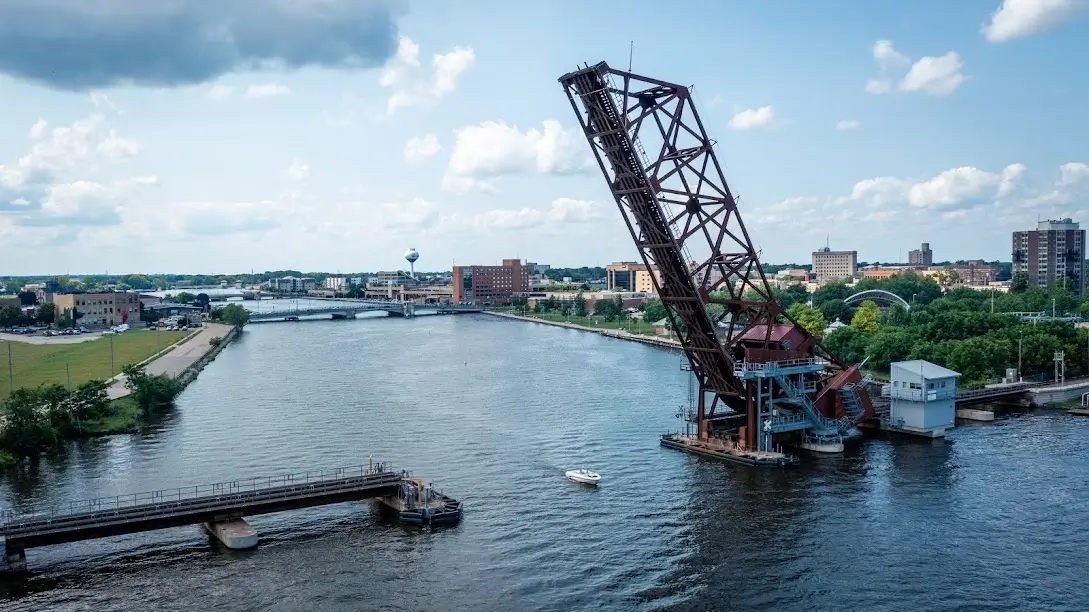 Lift bridge over river with boat below in urban cityscape